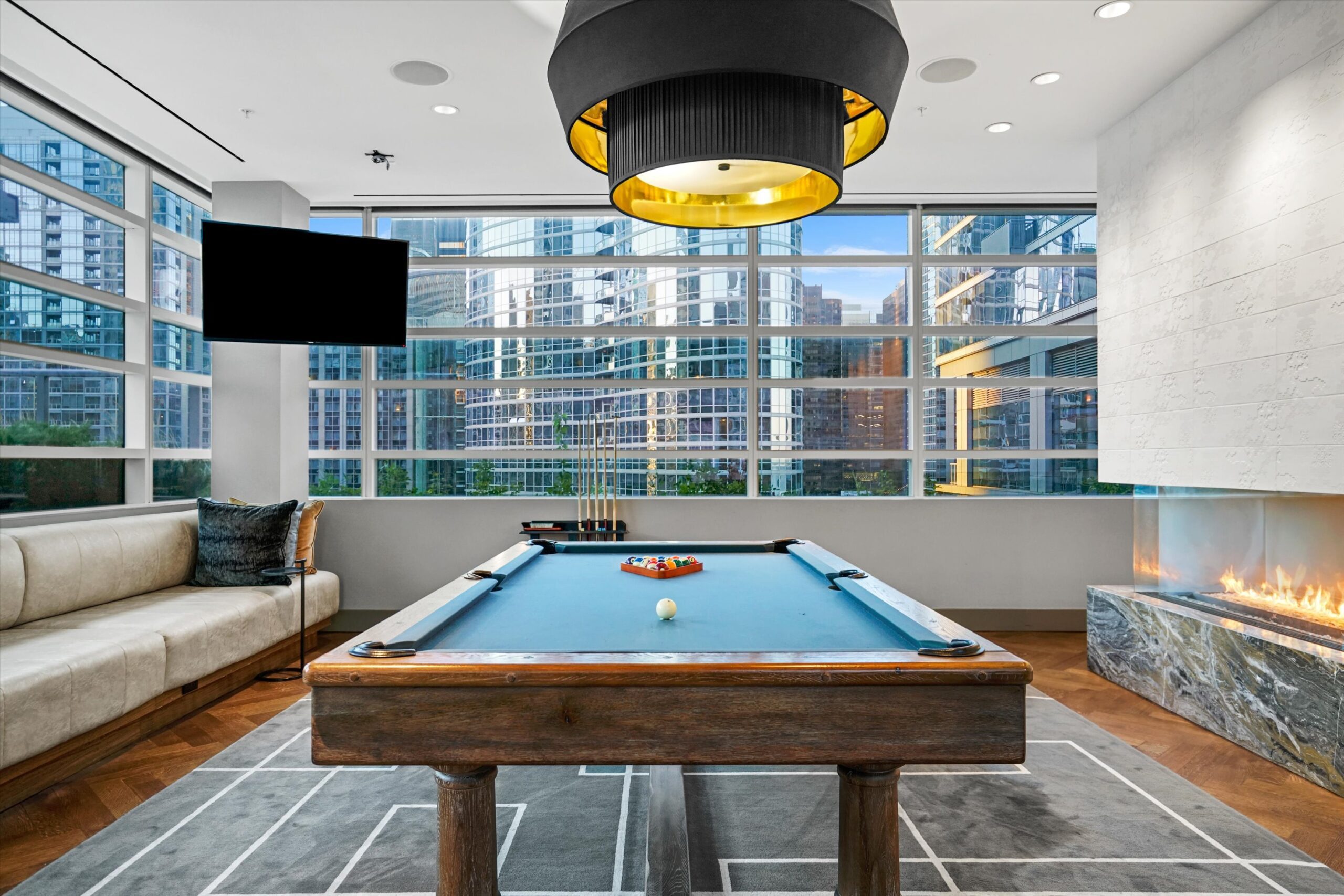 North Water Apartments game room with pool table and seating area and fire place with view of the city skyline